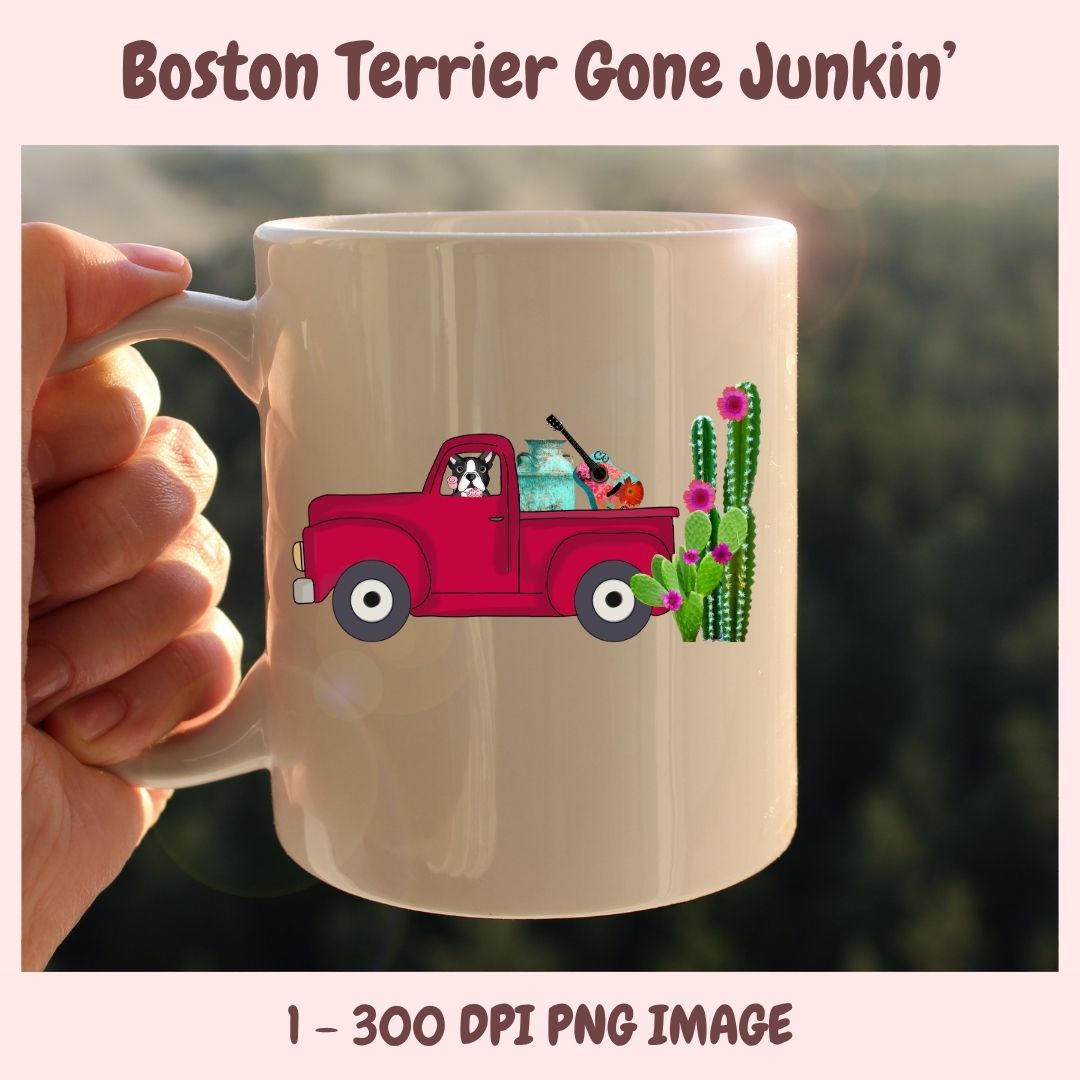 Beige mug with a red truck and Boston Terrier design, held by a hand against a blurred green background.