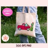 Tote bag with a red truck and cactus design held by a person outdoors.