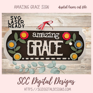 Decorative sign with 'amazing grace' text and floral designs on a wooden background, featuring SVG laser ready digital file by SCC Digital Designs.