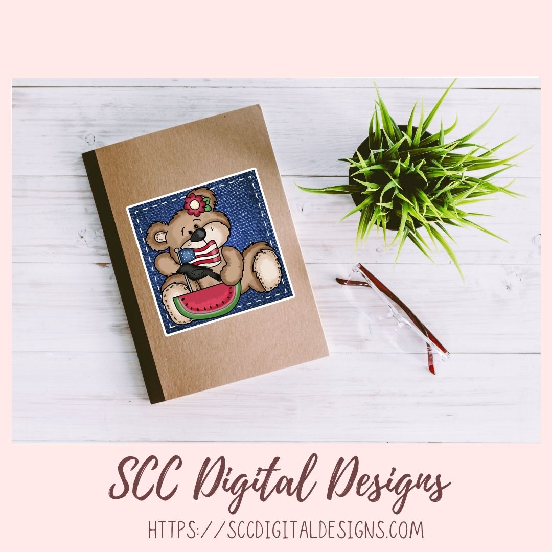 Notebook with teddy bear design on a wooden surface with a plant and pen.