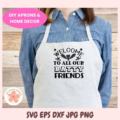 Person wearing a white apron with 'Welcome to all our batty friends' text, standing against a wooden background.