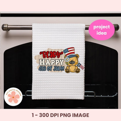 White towel with a bear wearing an American flag hat and text 'Happy 4th of July' hanging on a stove handle.