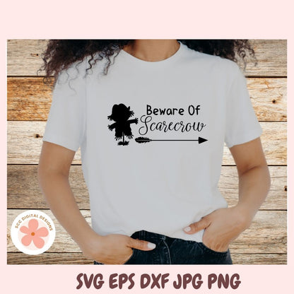 Person wearing a white t-shirt with 'Beware of Scarecrow' design on a wooden background