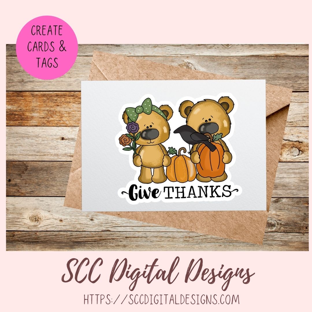 A fall-themed card design preview showing a white card with a die-cut sticker illustration of two teddy bears, pumpkins, a black bird, flowers, and the text 'Give THANKS'. The card is displayed over a kraft envelope on a rustic wood background, with a pink circle reading 'CREATE CARDS & TAGS' and 'SCC Digital Designs' branding at the bottom.