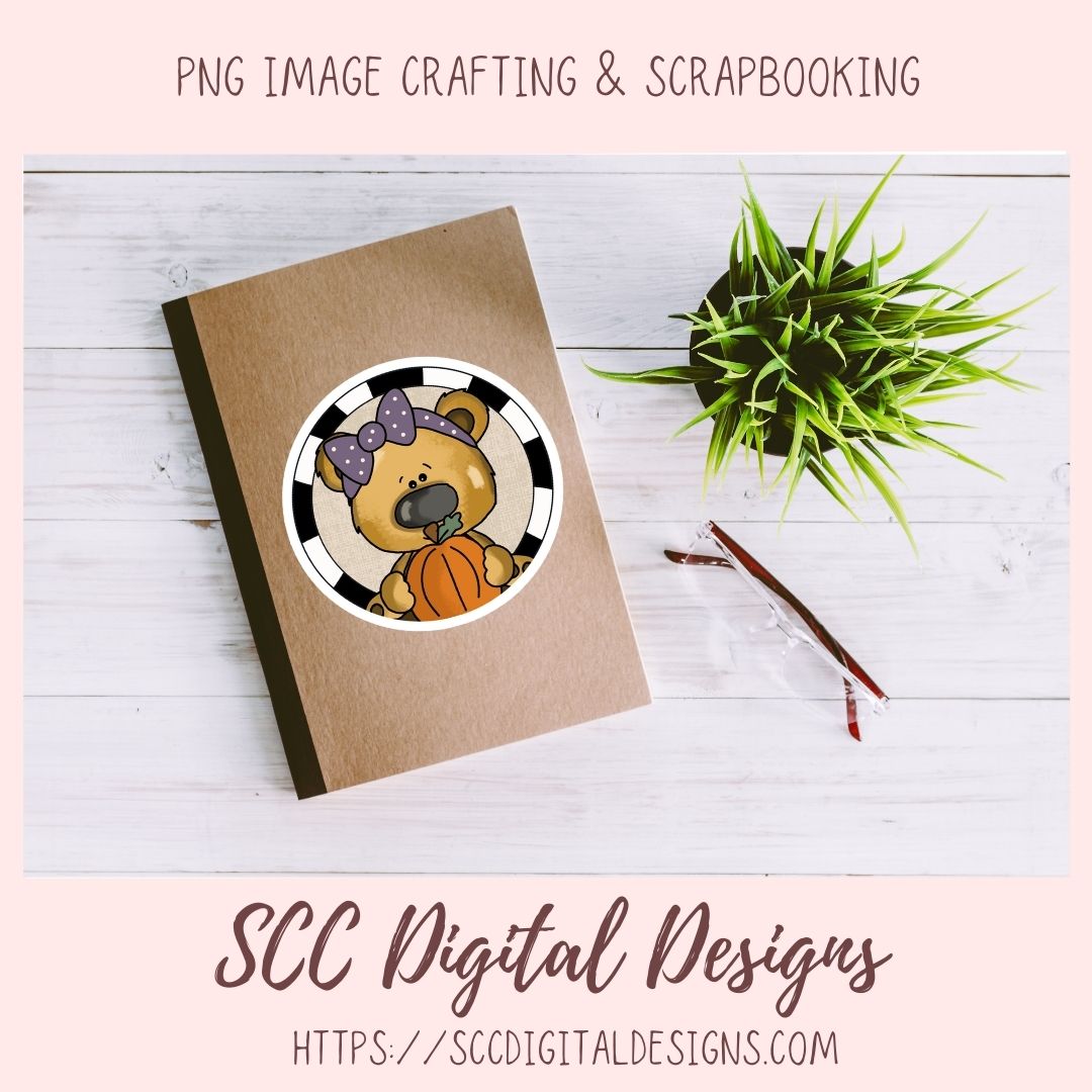 A digital scrapbooking design featuring a cute cartoon bear wearing a purple bow and holding a pumpkin, shown on a kraft paper notebook mockup. The image is branded with 'SCC Digital Designs' and includes a small potted plant and a pen on a white wood background.