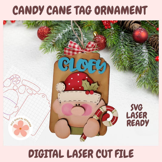 Candy cane tag ornament with 'Cloey' text, surrounded by Christmas decorations on a light pink background.