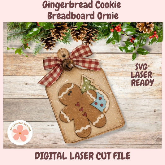 Digital preview of a gingerbread cookie breadboard ornament design, featuring a gingerbread man cookie with a tree and cupcake motif on a rustic tag with a red gingham ribbon, set on a wood plank background with holiday greenery. Text reads 'Gingerbread Cookie Breadboard Ornament,' 'SVG LASER READY,' and 'DIGITAL LASER CUT FILE.