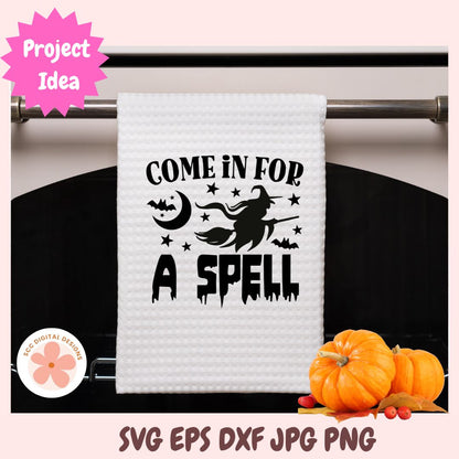 White towel with Halloween-themed text and graphics on a rack, with pumpkins in the background.