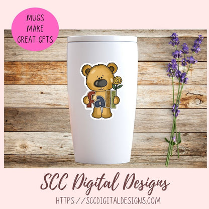 A white insulated tumbler with a lid, featuring a cartoon teddy bear graphic holding a book, displayed on a rustic wood background with purple flowers. A pink circular badge reads 'MUGS MAKE GREAT GFTS' and text at the bottom says 'SCC Digital Designs'.