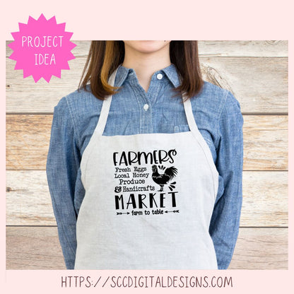 Person wearing a white apron with 'Farmers Market' text and graphics on a wooden background