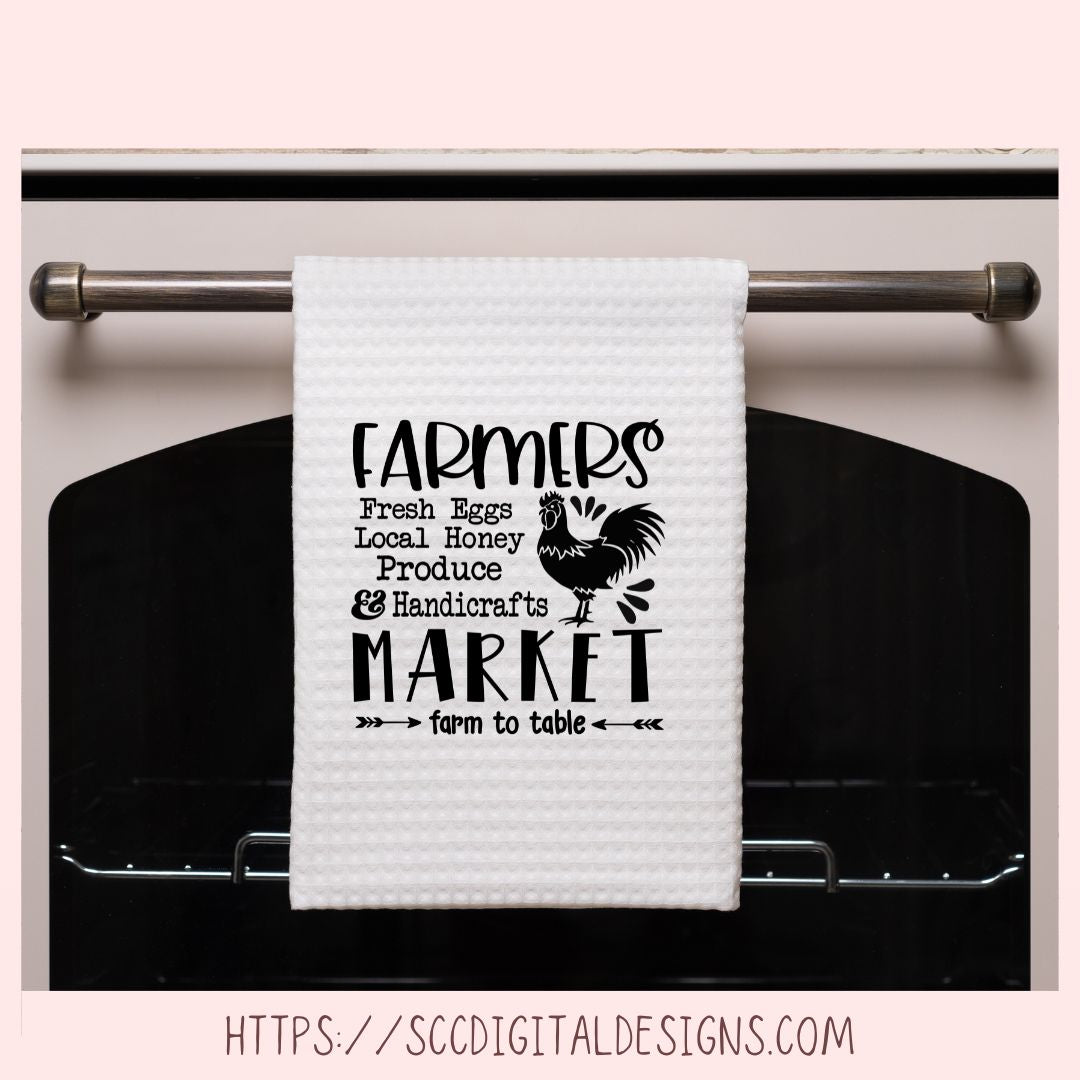 White towel with black text and rooster graphic hanging on a stove handle.