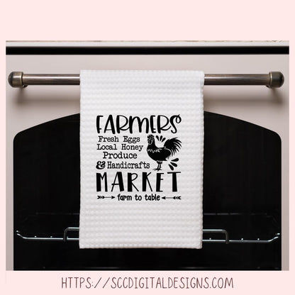 White towel with black text and rooster graphic hanging on a stove handle.