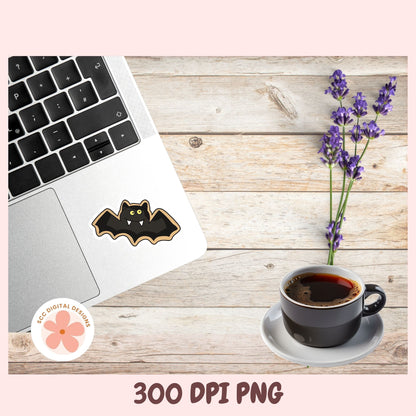 A digital mockup showing a black bat-shaped sticker with gold glitter-style outlines applied to the palm rest of a silver laptop on a rustic wood tabletop. A cup of coffee on a saucer and purple lavender sprigs sit nearby.
