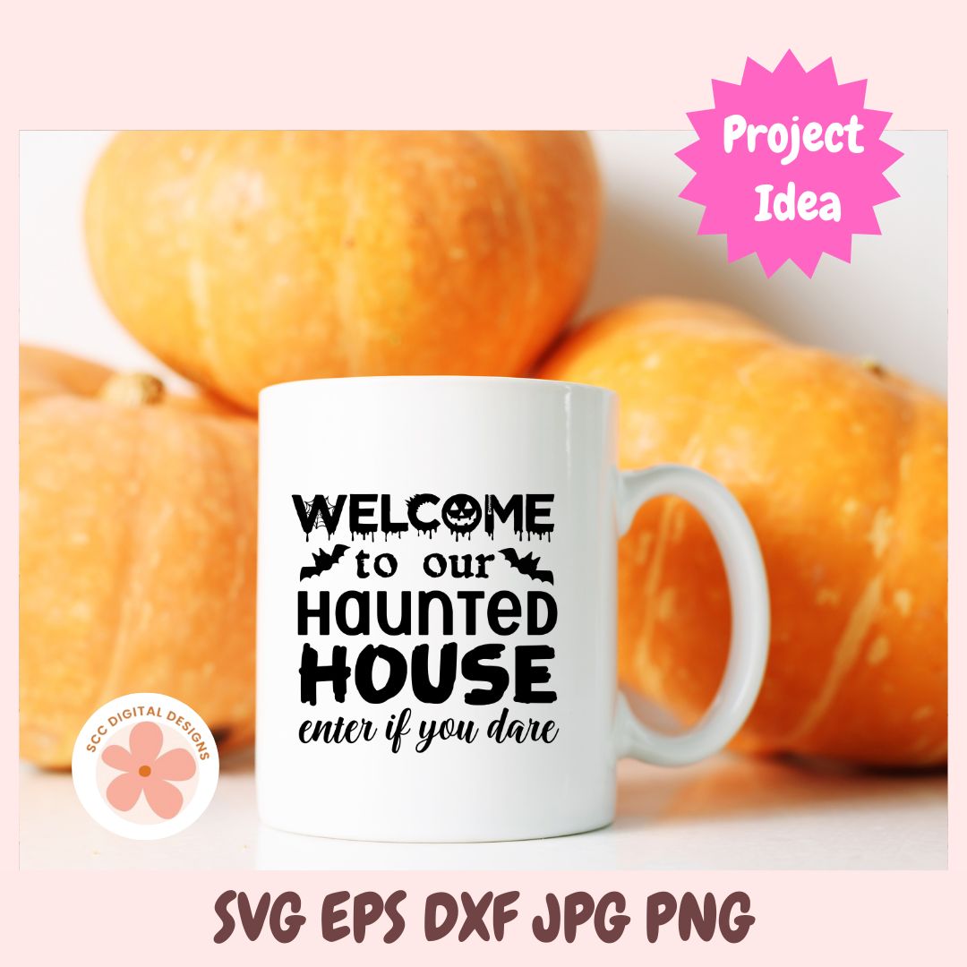 A white ceramic mug with black text reading 'WELCOME to our HAUNTED HOUSE enter if you dare' is shown in front of orange pumpkins. The image has a pink border with a pink 'Project Idea' badge and file-format text at the bottom.