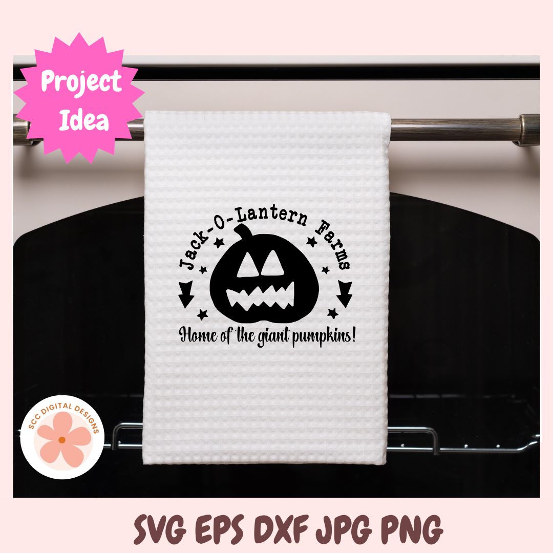 White towel with Halloween design hanging on a rack, featuring 'Jack-O-Lantern Farms' text and pumpkin graphic.