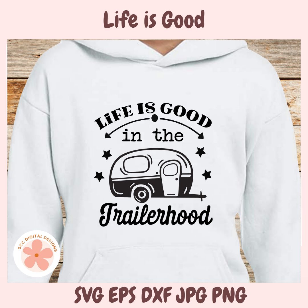 White hoodie with 'Life is Good in the Trailerhood' text and camper graphic on a wooden surface.