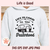 White hoodie with 'Life is Good in the Trailerhood' text and camper graphic on a wooden surface.