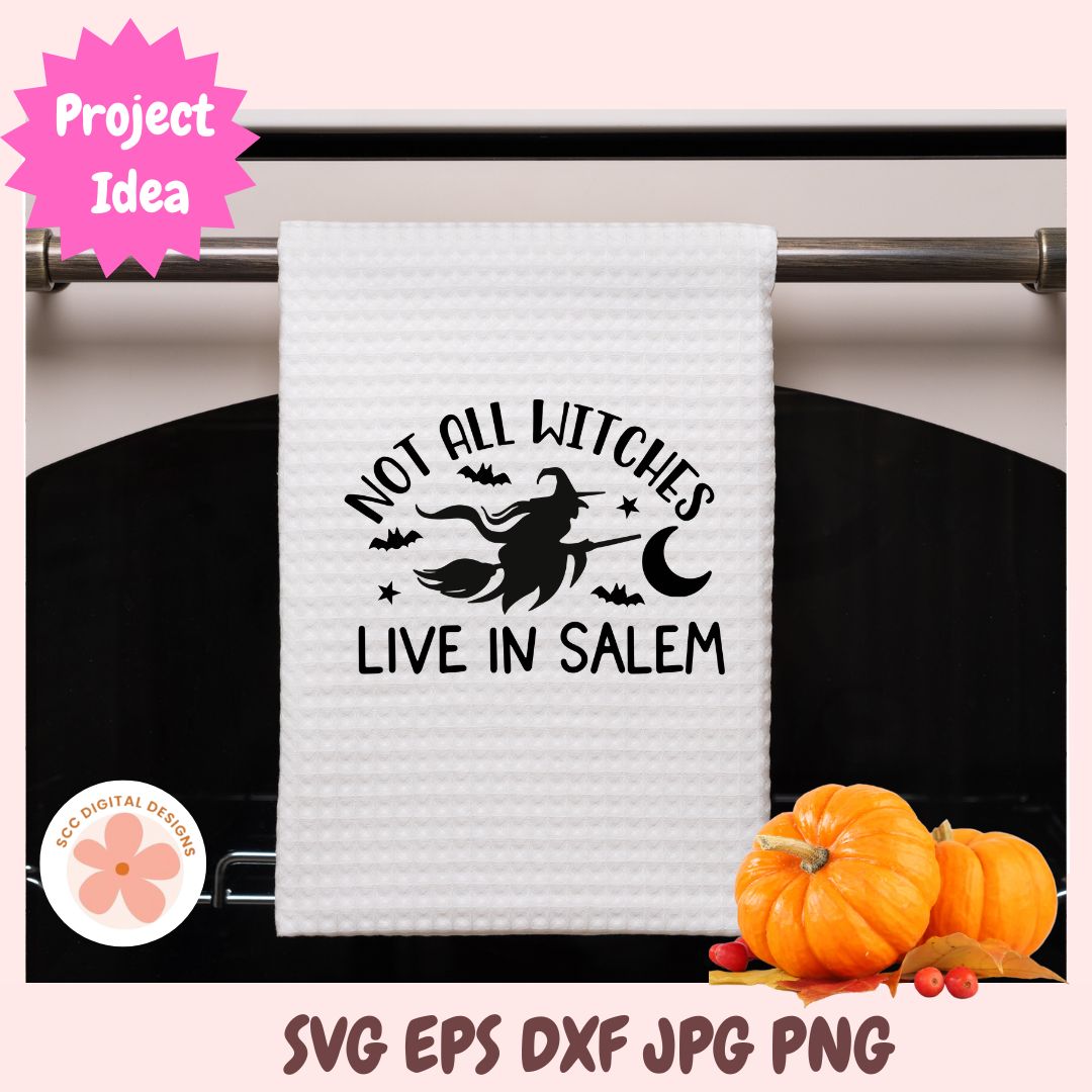 White towel with Halloween-themed design hanging on a rack, surrounded by pumpkins.
