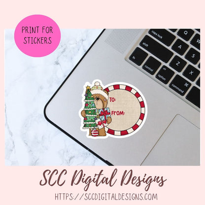 A holiday-themed sticker design shown on a laptop trackpad over a marble surface. The sticker features a teddy bear wearing a Santa hat and coat beside a red-and-white striped circular frame with the text 'TO:' and 'FROM:'.