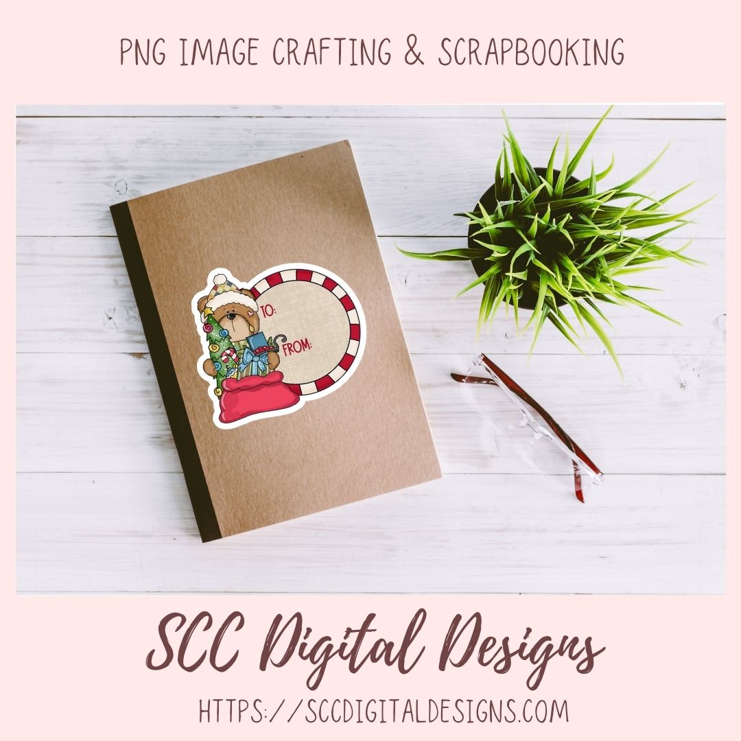 A kraft paper notebook or cardstock sheet with a die-cut sticker showing a teddy bear in a Santa hat and the words 'MERRY FROM SC', styled on a white wood background with a small green plant and a pencil. Text at the top reads 'PNG IMAGE CRAFTING & SCRAPBOOKING' and text at the bottom reads 'SCC Digital Designs' with a website URL.