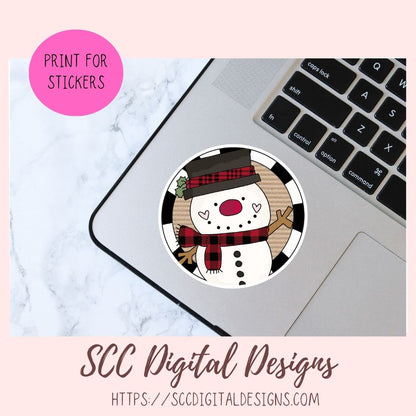 A circular sticker design featuring a cartoon snowman wearing a black and red plaid hat and scarf, shown placed on a laptop trackpad. The image includes a pink circle reading 'PRINT FOR STICKERS' and text at the bottom reading 'SCC Digital Designs' with a website URL.