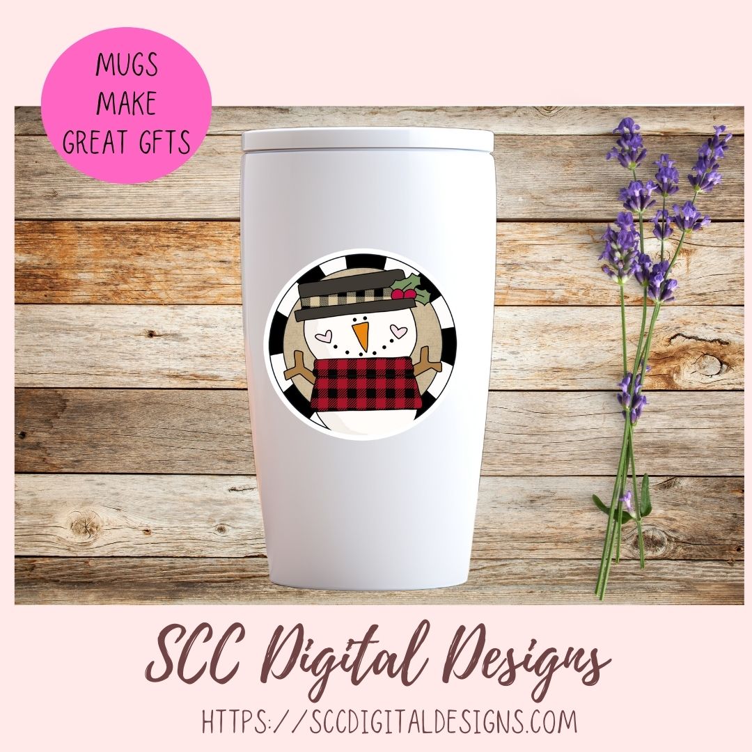 A white insulated tumbler with a lid is centered on a rustic wood plank background, decorated with a circular snowman graphic wearing a black-and-red plaid hat and scarf. Pink branding text at the top left reads 'MUGS MAKE GREAT GFTS,' and the bottom text reads 'SCC Digital Designs' with a website URL.