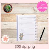 Notebook with a sticker of a goat on a wooden surface with a pen and plant.
