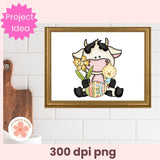 Framed illustration of a cow holding a baby and an Easter egg on a white brick wall.