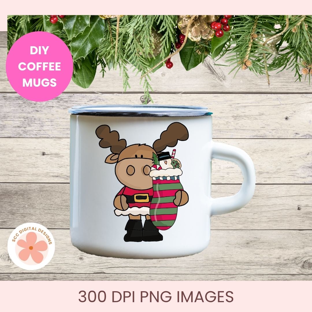 A white enamel-style coffee mug with a blue rim, featuring a cartoon moose holding a striped stocking. The mug is shown on a rustic wood background with holiday greenery and a pink 'DIY COFFEE MUGS' badge.