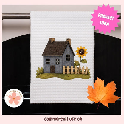 A white waffle-weave kitchen towel featuring an embroidered design of a small gray house, a yellow sunflower, and a wooden fence, hanging on a dark oven door. The image includes decorative overlays: a pink 'PROJECT IDEA' badge, a circular 'BEE DIGITAL DESIGNS' logo, and a pink 'commercial use ok' banner at the bottom.
