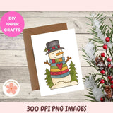 Christmas card with a snowman design on a wooden surface with decorative elements.