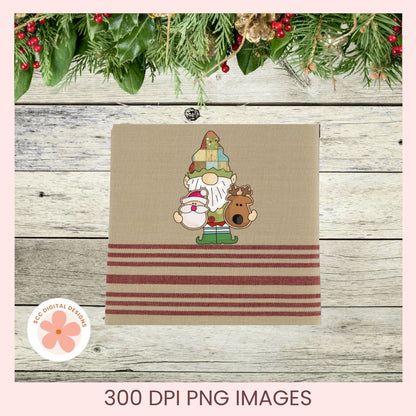 A square fabric napkin or small towel in beige with three horizontal dark red stripes near the bottom and a central embroidered-style holiday gnome design, shown on a rustic wood plank background with green garland and red berries. Text at the bottom reads '300 DPI PNG IMAGES' and a circular logo says 'JCC DIGITAL DESIGNS'.