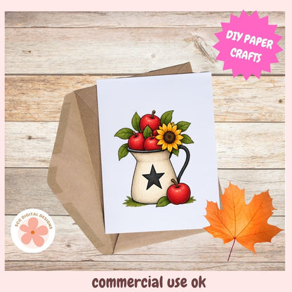 A printed card or art print featuring an autumn-themed illustration of red apples, a sunflower, and green leaves in a cream pitcher with a black star, shown with a brown envelope on a wood plank background. A pink starburst says 'DIY PAPER CRAFTS,' and the bottom text reads 'commercial use ok.