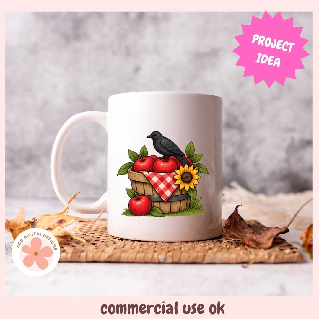 A white ceramic mug with a printed design of a black raven perched on a basket of red apples, green leaves, and a sunflower, set on a woven mat with autumn leaves. The image includes a pink 'PROJECT IDEA' badge and a 'commercial use ok' label.