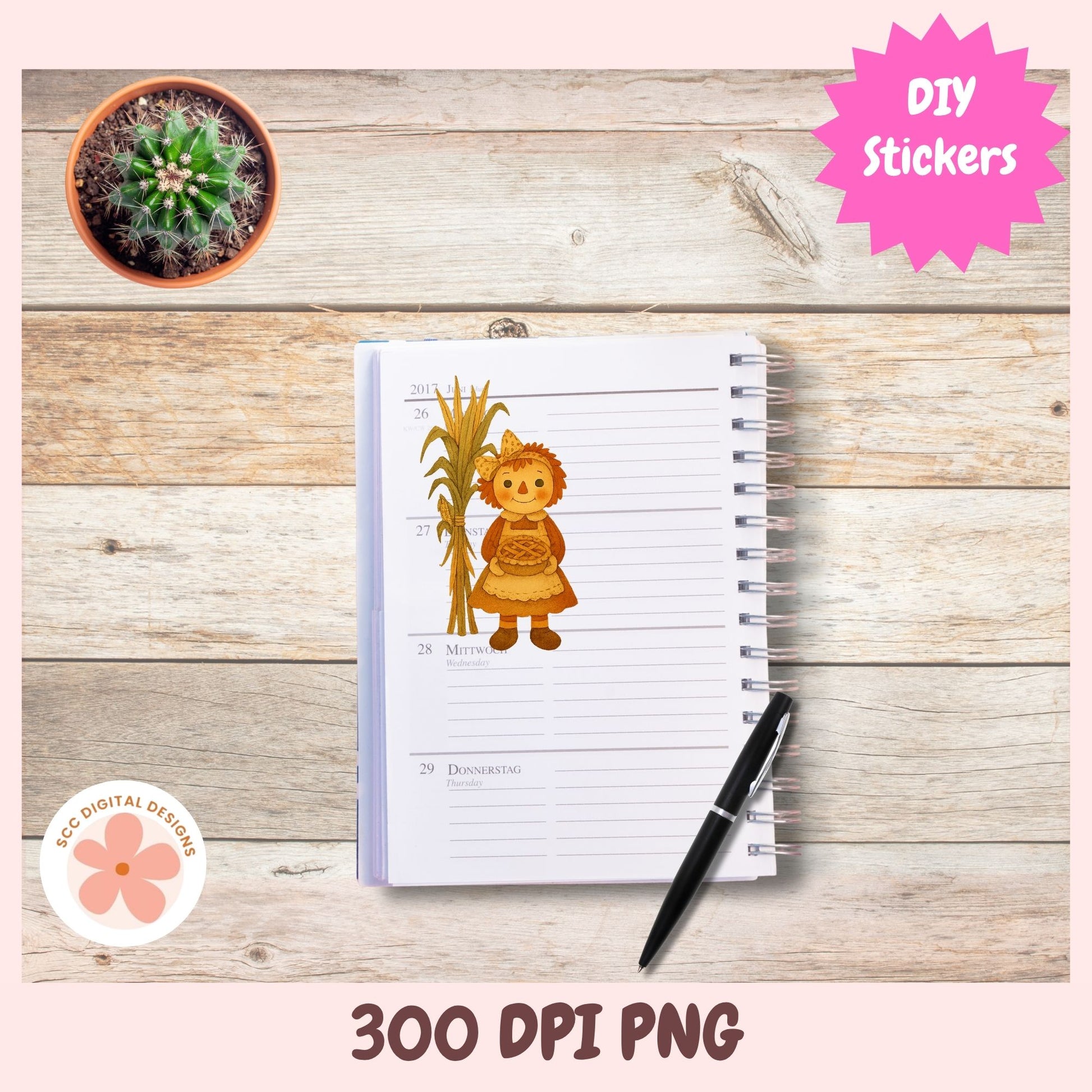 A spiral-bound planner or notepad shown on a rustic wood background, featuring a printed autumn-themed sticker illustration of a lion cub holding a cornstalk. A black pen rests on the notepad, with decorative pink badges reading DIY Stickers and 300 DPI PNG, plus a small cactus pot in the corner.