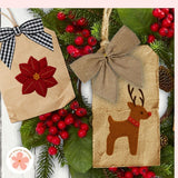 Two Christmas-themed paper bags with poinsettia and reindeer designs on a festive background.