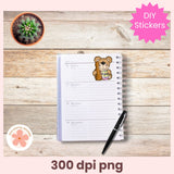 Notebook with a teddy bear sticker on a wooden surface with a pen and cactus plant.