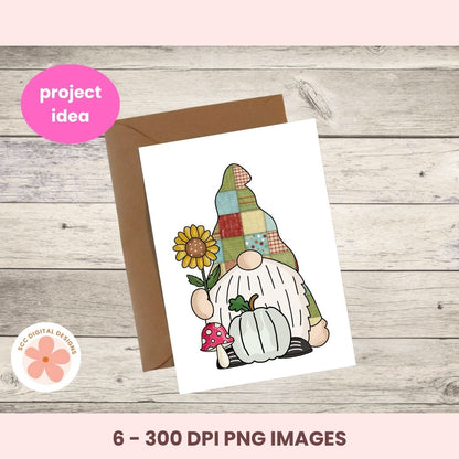 A printed card featuring a patchwork gnome illustration with a sunflower, mushroom, and pumpkin, shown with a brown envelope on a wood plank background. Pink text banners read 'project idea' and '6 - 300 DPI PNG IMAGES'; a circular 'DOC DIGITAL DESIGNS' logo appears at lower left.