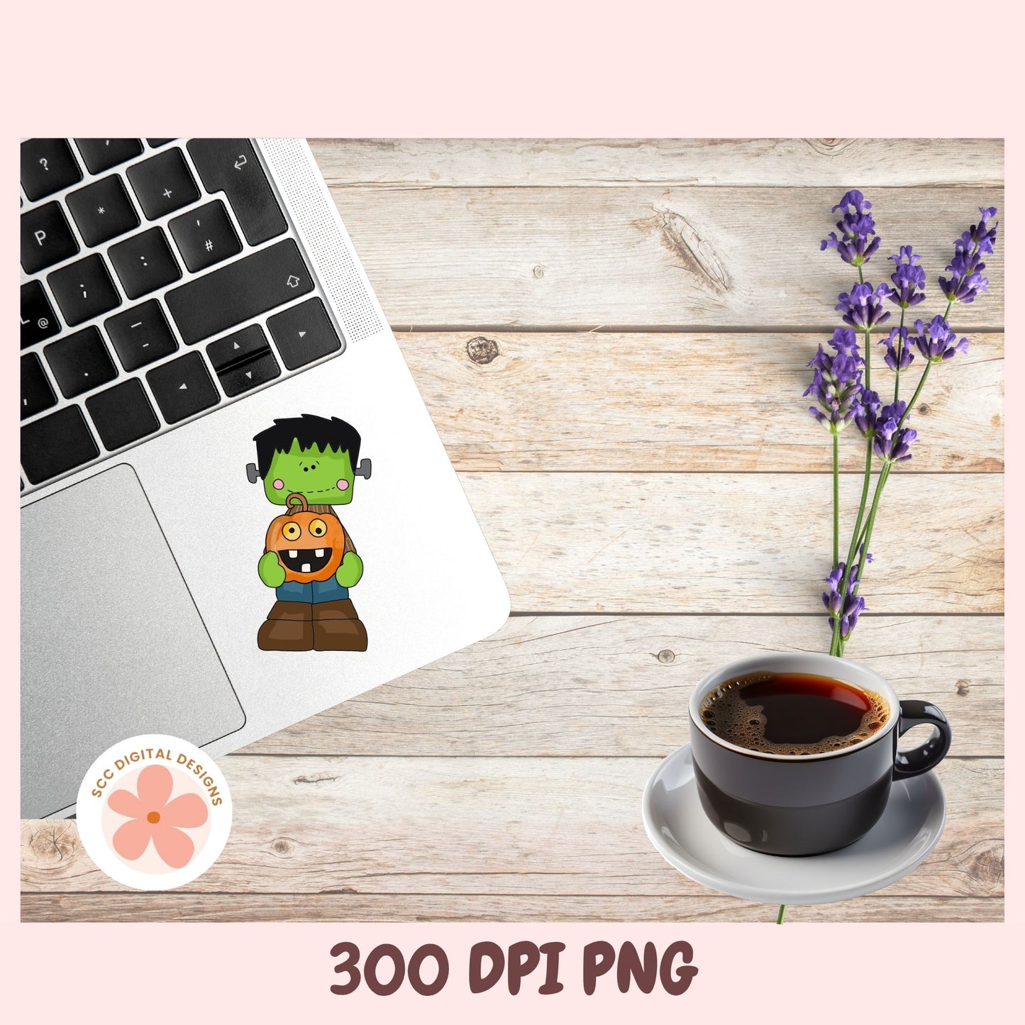 A flat-lay mockup showing a cartoon Frankenstein's monster sticker applied to a silver laptop, alongside a cup of coffee, lavender flowers, and a wooden tabletop. The image has a pink border with text reading '300 DPI PNG' and a circular 'SEC DIGITAL DESIGNS' logo.