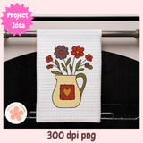 White towel with floral design hanging on a stove handle, featuring a heart on a pink background.