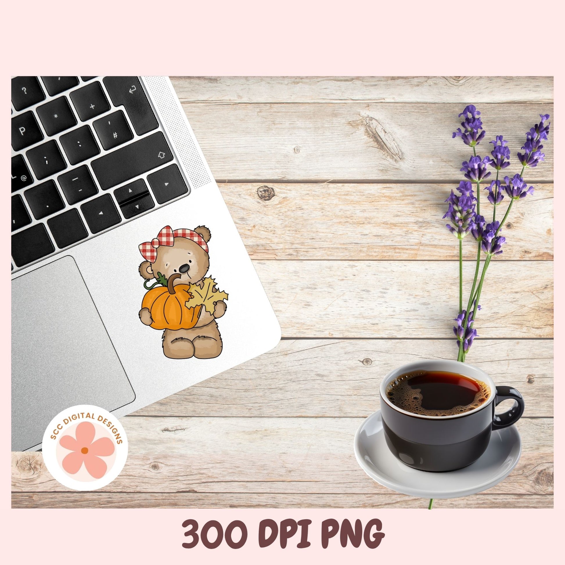 A digital sticker design of a cute autumn bear holding a pumpkin and a star, shown applied to a laptop sticker. The scene is styled on a rustic wooden background with a laptop, a cup of coffee, and purple lavender flowers, framed by a pink border with '300 DPI PNG' text at the bottom.