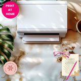 White printer on a desk with a mug, plant, and printed sheet of paper.