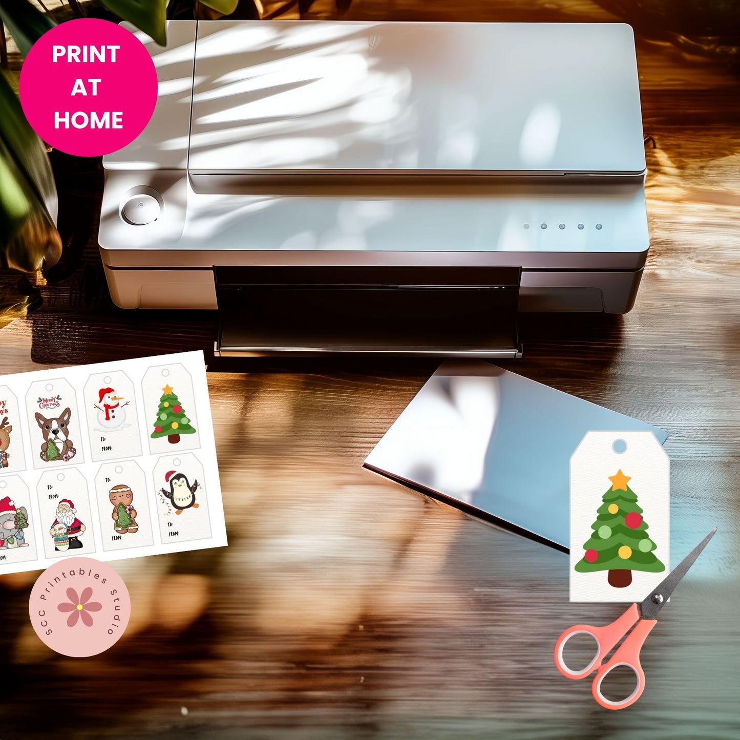 Printer on a table with printed Christmas-themed cards and a tree tag, scissors, and 'Print at Home' text.