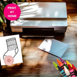 Printer on a wooden surface with a printed sock design and colorful crayons.