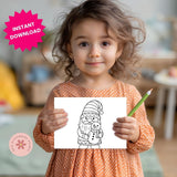 Child holding a coloring sheet with a gnome and snowman drawing, with 'Instant Download' text overlay.