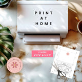 Printer with 'Print at Home' text on a marble surface with a plant and cup of coffee.