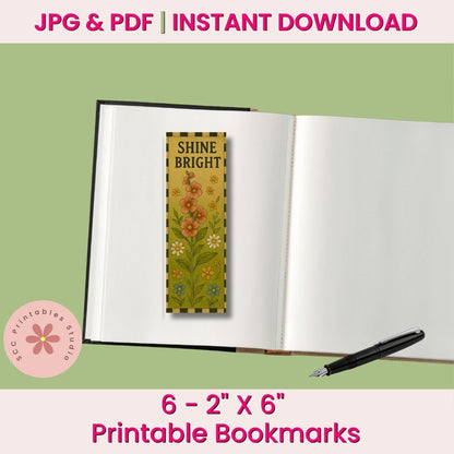 A printable bookmark design shown inside an open book mockup on a pale green background, with text reading 'JPG & PDF | INSTANT DOWNLOAD', '6 - 2" X 6" Printable Bookmarks', and a pink circular logo for 'SCC Printables Studio'. The bookmark features a floral pattern with the words 'SHINE BRIGHT!' in black text.