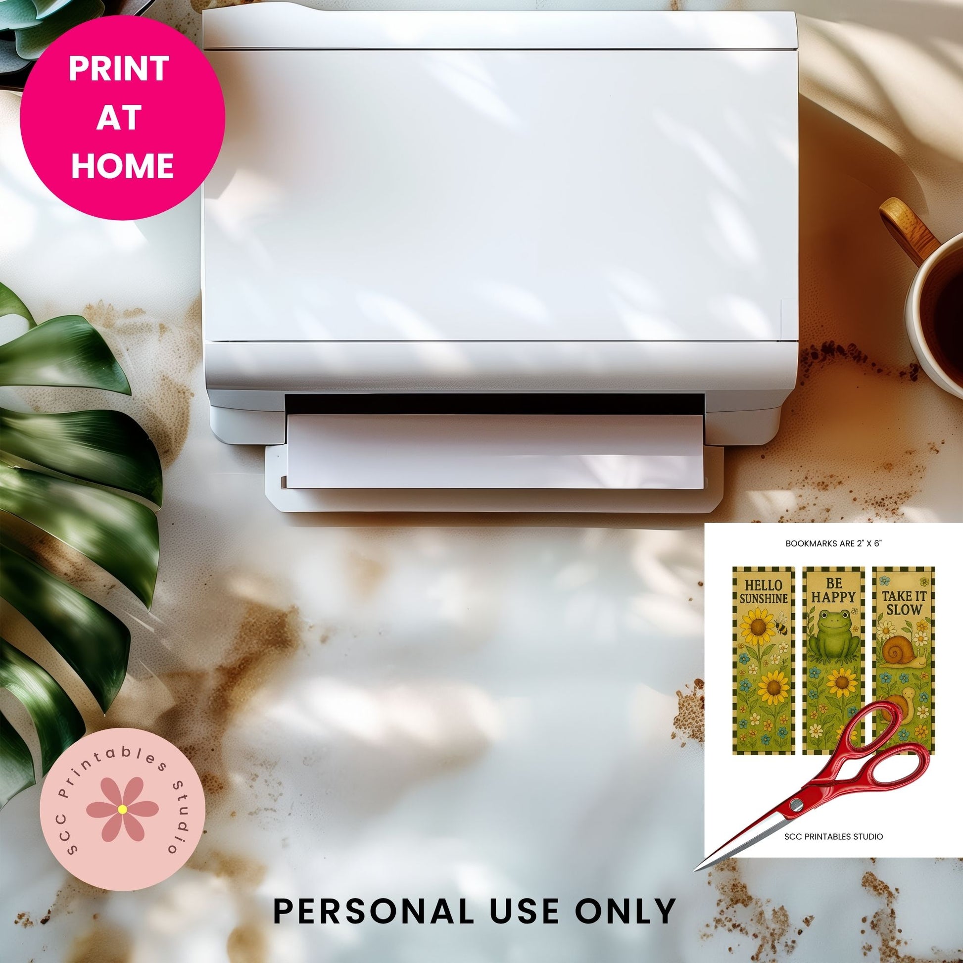 A white desktop printer shown from above on a marble-like surface with sunlight shadows, a pink 'PRINT AT HOME' badge, a pink 'SCC Printables Studio' logo, and a small inset showing decorative bookmarks and the text 'PERSONAL USE ONLY'.
