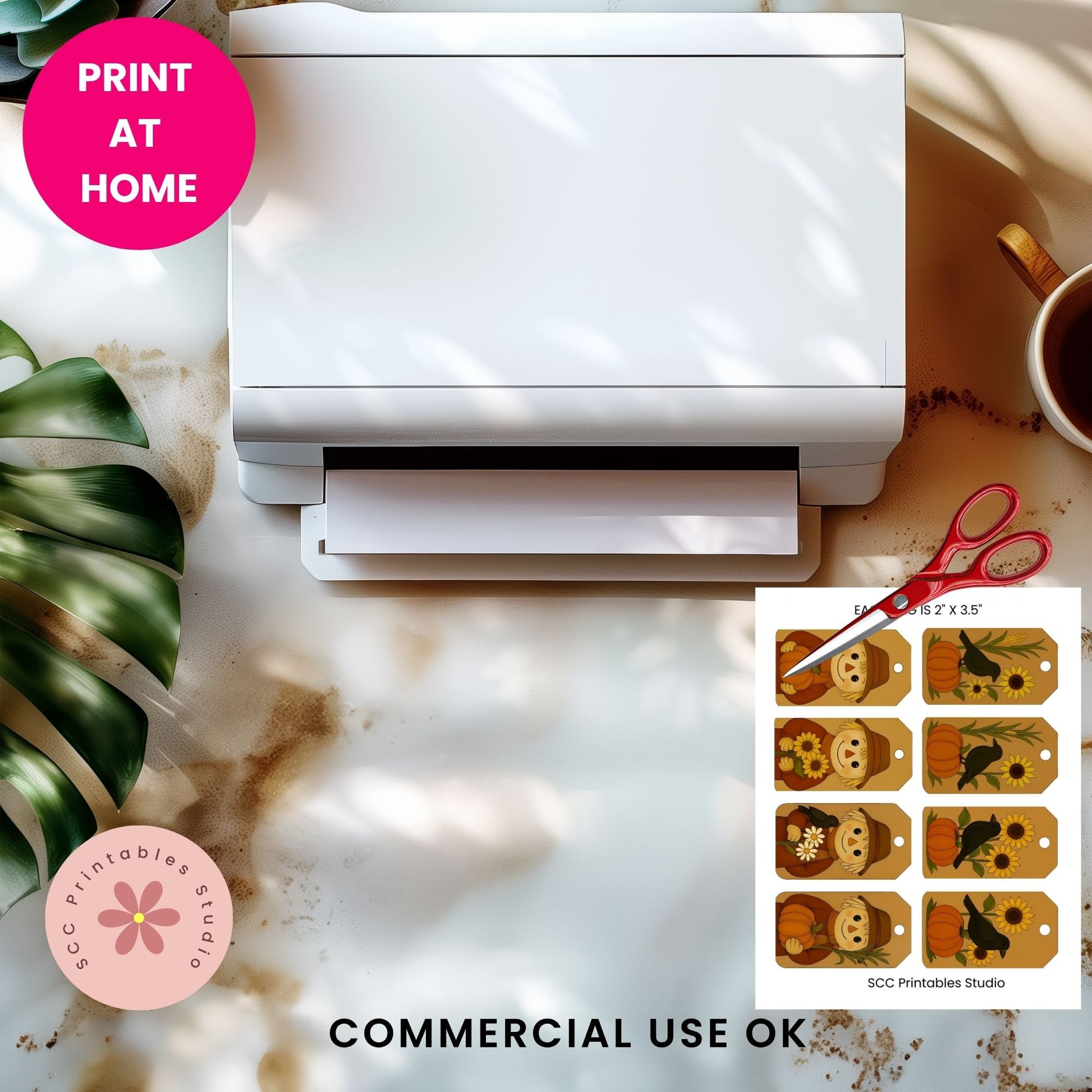 A white printer shown from above on a marble-like surface with a pink 'PRINT AT HOME' badge, a cup of coffee, green leaves, scissors, and a printed sheet of decorative tags. Text at the bottom reads 'COMMERCIAL USE OK' and 'SCC Printables Studio' appears on the print sheet.