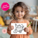 Child holding a coloring book with a wagon and rabbit illustration, in a home setting.